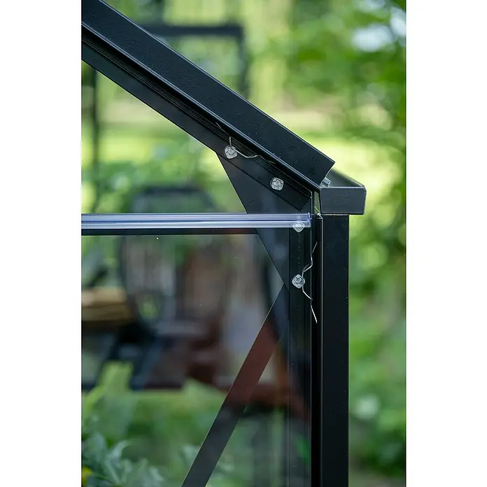 Halls Gewächshaus Popular 106 - Außenmaß inkl. Dachüberstand (B x T): 193 x 319 cm, Einscheibensicherheitsglas, 3 mm, Schwarz - Detailaufnahme eines schwarzen Gewächshauses mit Glasplatten, befestigt mit Schrauben und Drahtklammern vor grünem Hintergrund.