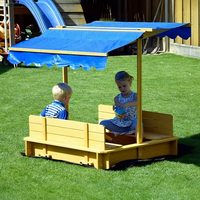 Dobar Sandkasten - 112 x 112 x 112 cm, Höhenverstellbares Dach - Kinder spielen in einem gelben Sandkasten mit blauem Sonnendach im Garten.