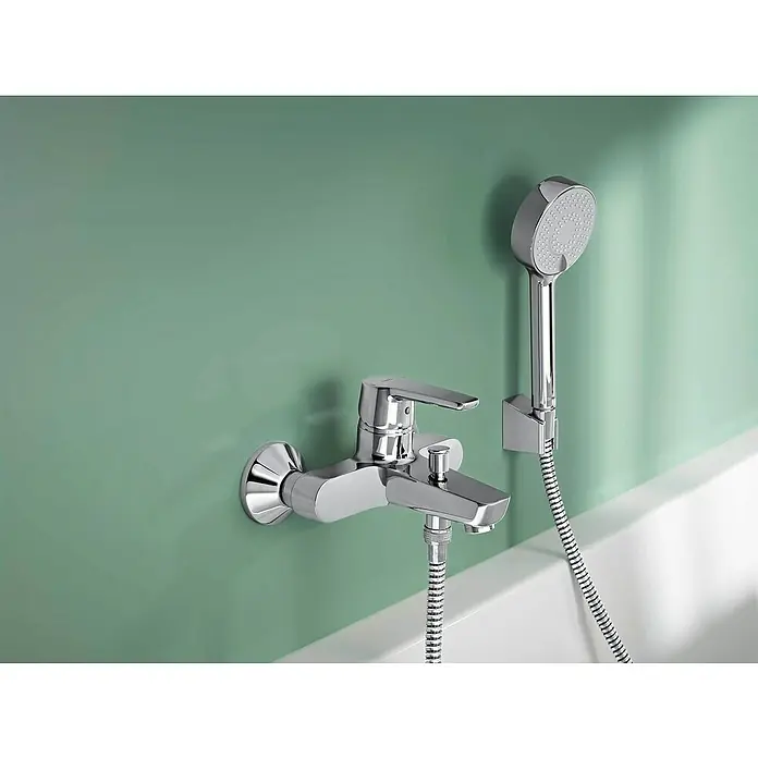 Hansa Polo Badewannenarmatur - Ausladung Armatur: 157 mm, Chrom, Glänzend - Nahaufnahme einer glänzenden Badewannenarmatur mit Handbrause an einer grün gestrichenen Wand. Elegantes Design für moderne Badezimmer.