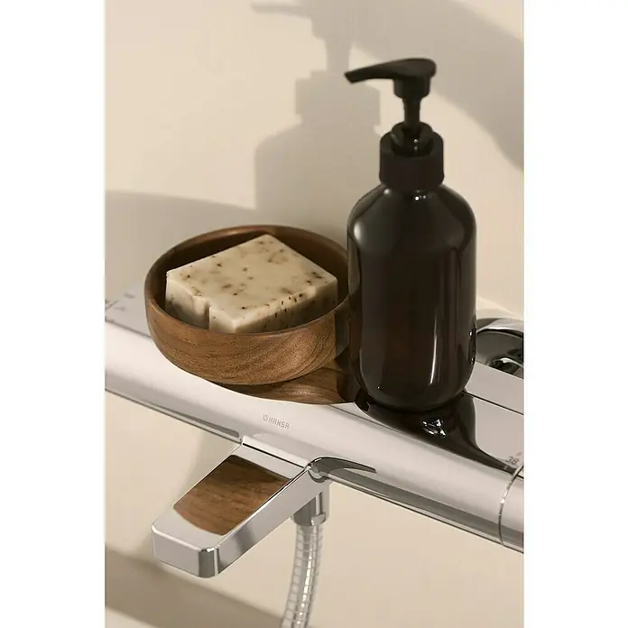 Hansa UP-Brausethermostat Optima - Chrom, Glänzend - Seifenschale mit Seife und eine braune Seifenpumpe auf einer silbernen Armatur mit Holzelement. Stilvolle Badaccessoires.