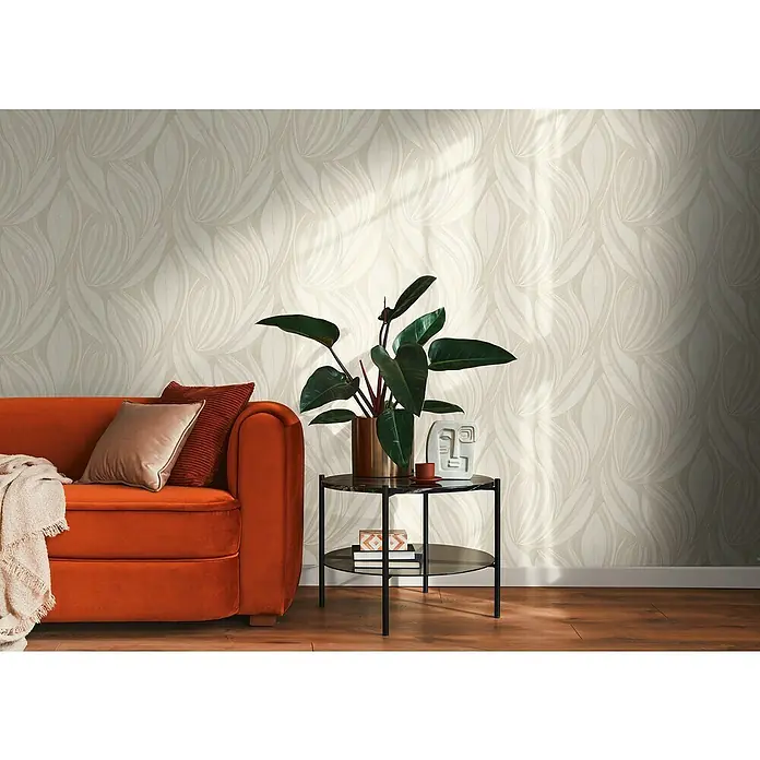 A.S. Création Metropolitan Stories Hot Spots Vliestapete Floral - Creme-Beige-Hellgrau, Floral, 10,05 x 0,53 m - Elegante Wohnzimmergestaltung mit einer stilvollen orangefarbenen Couch, einem Beistelltisch mit einer Zimmerpflanze und einer dekorativen Wandtapete.