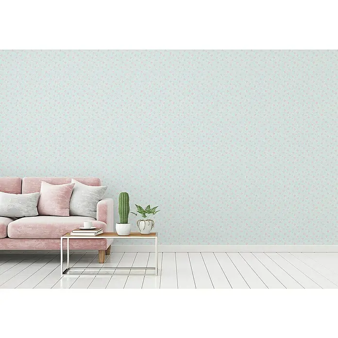 A.S. Création Maison Charme Vliestapete Blümchen - Blau-Rosa-Weiß, Floral, 10,05 x 0,53 m - Einrichtung mit rosa Sofa, Beistelltisch und Dekoration vor einer blau gemusterten Wand. Das harmonische Interieur strahlt Gemütlichkeit aus.