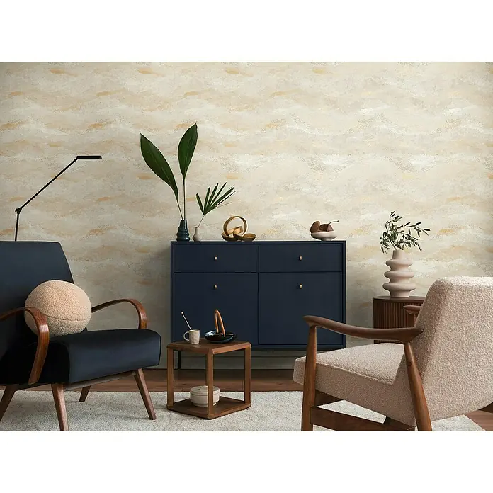 A.S. Création Metropolitan Stories Hot Spots Vliestapete Wellengrafik - Creme-Grün-Gold, Wellen, 10,05 x 0,53 m - Elegantes Wohnzimmer-Interieur mit marineblauem Sideboard, stilvollen Sesseln und dekorativen Elementen vor einer gemusterten Tapete.