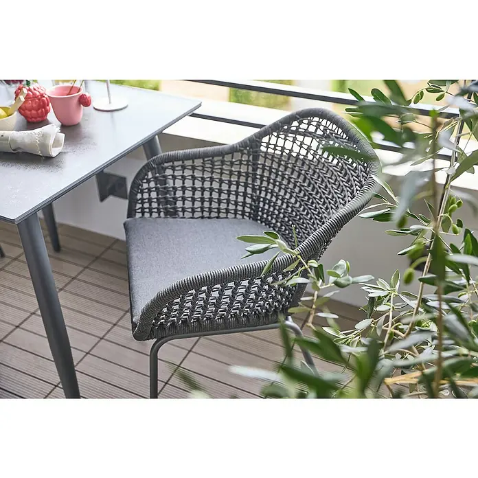 Sunfun Sarah Gartensessel Rope - Stahl, Olefin, Night Grey, B x T x H: 59 x 58 x 80 cm - Moderner grauer Rattansessel mit Sitzkissen und Metallgestell neben einem Tisch auf einer Terrasse.