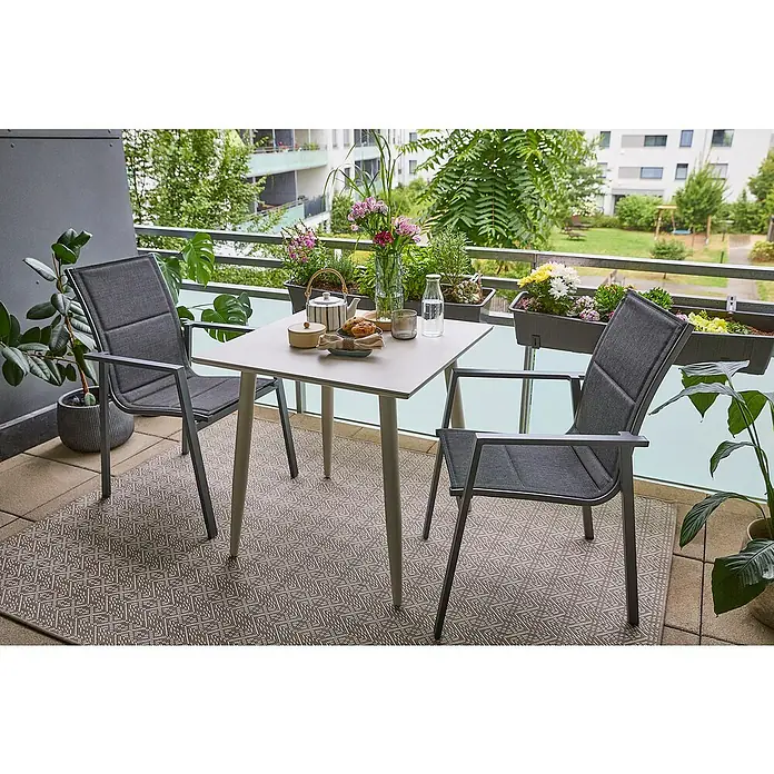 Sunfun Balkonmöbel-Set Solo/Maja II - 3 -tlg., Aluminium, Sintered Stone, Textilen, Anthrazit/Light-Greige, Gartenstuhl stapelbar - Nahaufnahme eines Balkons mit einem quadratischen Tisch, zwei grauen Stühlen und Blumenkästen am Geländer.