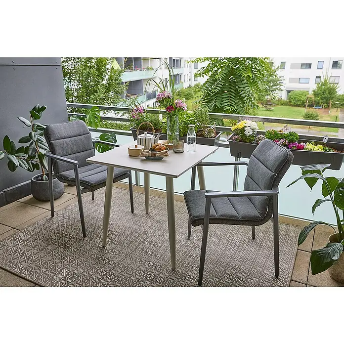 Sunfun Balkonmöbel-Set Solo/Solo Rope - 5 -tlg., Aluminium, Sintered Stone, Olefin, Light-Greige, Gartenstuhl stapelbar - Balkon mit grauem Outdoor-Teppich, Tisch und Stühlen. Pflanzenkästen schmücken die Brüstung und sorgen für eine gemütliche Atmosphäre.