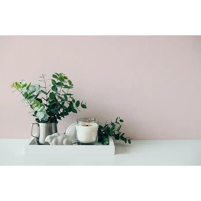 A.S. Création Maison Charme Vliestapete - Rosa, Uni, 10,05 x 0,53 m - Kerze, Topfpflanze und Hasenfigur auf einem weißen Tablett. Eine elegante Dekoration mit Kerze und Pflanzenarrangement auf weißem Untergrund.
