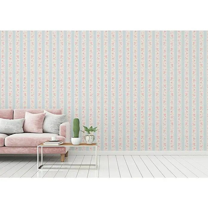 A.S. Création Maison Charme Vliestapete Vertikale Blümchen - Blau-Weiß-Rosa, Floral, 10,05 x 0,53 m - Einladender Raum mit pastellfarbenem Sofa, Akzenttisch mit Pflanzen und Tasse, vor einer floralen Streifentapete.
