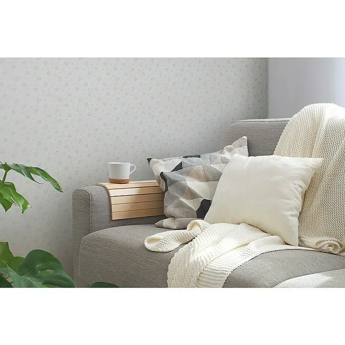 A.S. Création Maison Charme Vliestapete Blümchen - Hellgrau-Blau-Weiß, Floral, 10,05 x 0,53 m - Gemütliches Sofa mit Kissen und Decke, eine Tasse Kaffee auf dem Beistelltisch.