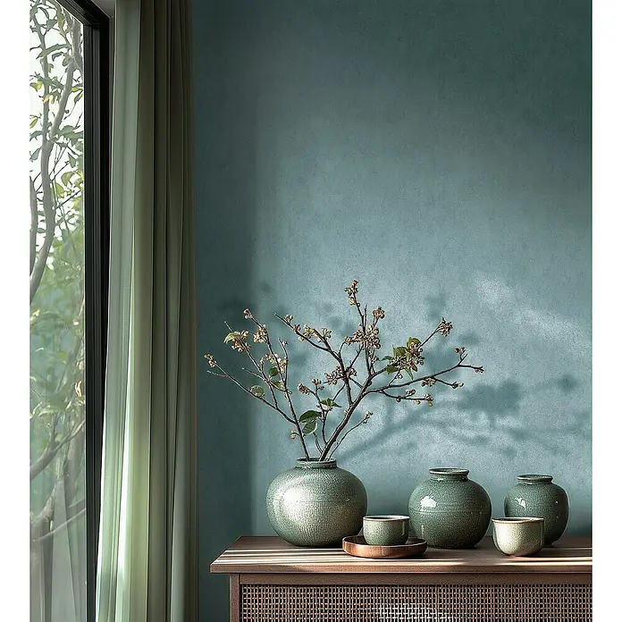 A.S. Création Metropolitan Stories Hot Spots Vliestapete - Blau-Metallic, Uni, 10,05 x 0,53 m - Nahaufnahme von dekorativen Keramikvasen und Schalen auf einem Holzschrank vor einer blaugrünen Wand.