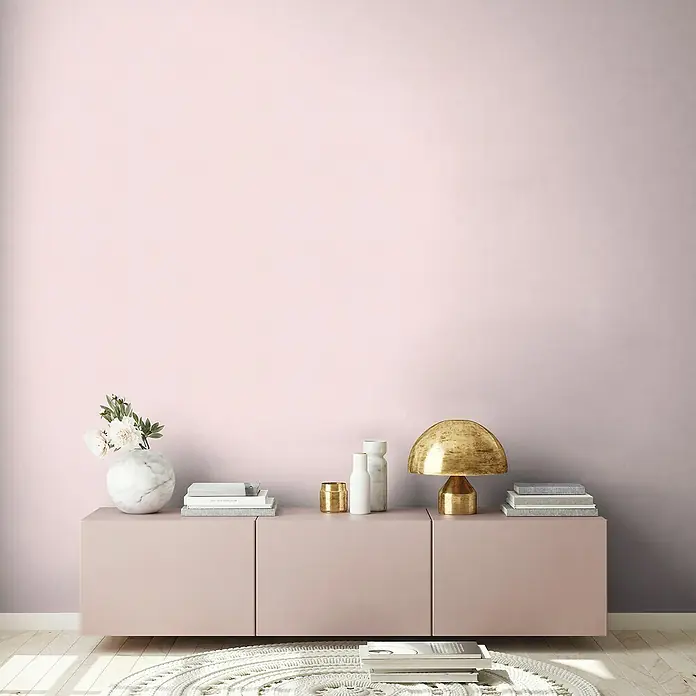 A.S. Création Maison Charme Vliestapete - Rosa, Uni, 10,05 x 0,53 m - Modernes Interieur mit einem Sideboard in Rosa, dekoriert mit einer Marmorvase, Büchern und einer goldenen Lampe.