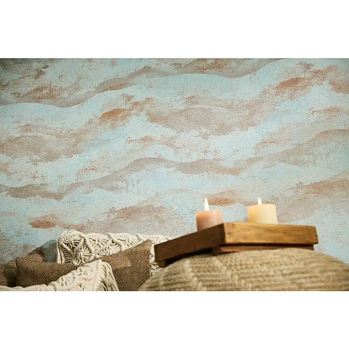 A.S. Création Metropolitan Stories Hot Spots Vliestapete Wellengrafik - Hellblau-Braun-Metallic, Wellen, 10,05 x 0,53 m - Dekorative Kerzen auf einem Holztablett, platziert auf einem gemütlichen Kissen, vor einer kunstvollen Wand.