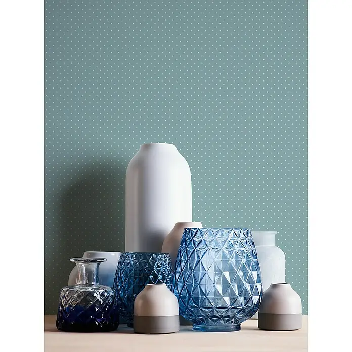 A.S. Création Maison Charme Vliestapete Punkte - Blau-Weiß, Grafisch, 10,05 x 0,53 m - Sammlung von Vasen in verschiedenen Formen und Farben auf einem Tisch, darunter blaue Glasvasen und weiße Keramikvasen.