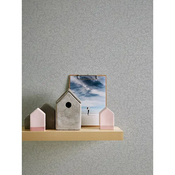 A.S. Création Maison Charme Vliestapete Ranken - Grau-Weiß, Floral, 10,05 x 0,53 m - Dekorative Häuschen und ein Clipboard mit einem Foto, die auf einem Regal vor einer floralen Tapete stehen.