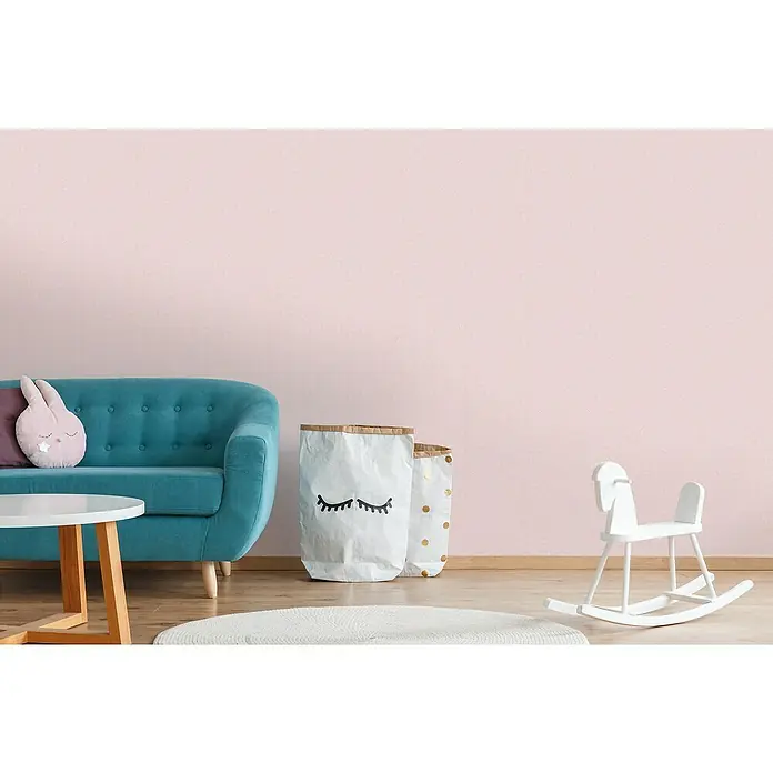A.S. Création Maison Charme Vliestapete Ranke - Rosa-Weiß, Floral, 10,05 x 0,53 m - Ein gemütliches Kinderzimmer mit mintgrünem Sofa, Spielzeug und dekorativen Aufbewahrungssäcken vor einer rosa Wand.