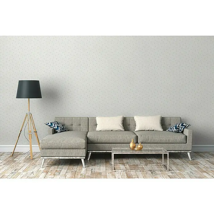A.S. Création Maison Charme Vliestapete Blümchen - Hellgrau-Blau-Weiß, Floral, 10,05 x 0,53 m - Moderne Wohnzimmerszene mit grauem Sofa, dekorativen Kissen und einer stilvollen Stehlampe, die eine gemütliche Atmosphäre schaffen.