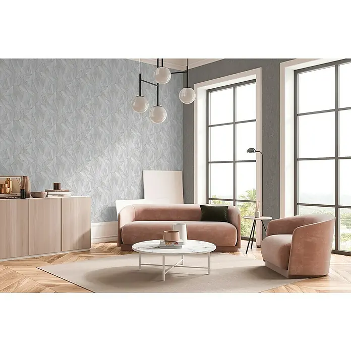 A.S. Création Daniel Hechter 7 Vliestapete Grafische Dreiecke - Grau-Metallic-Silber, Grafisch, 10,05 x 0,53 m - Ein stilvolles Wohnzimmer mit einem modernen Sofa, einem Sessel und einem Couchtisch auf einem hellen Teppich. Die Tapete hat ein geometrisches Muster.