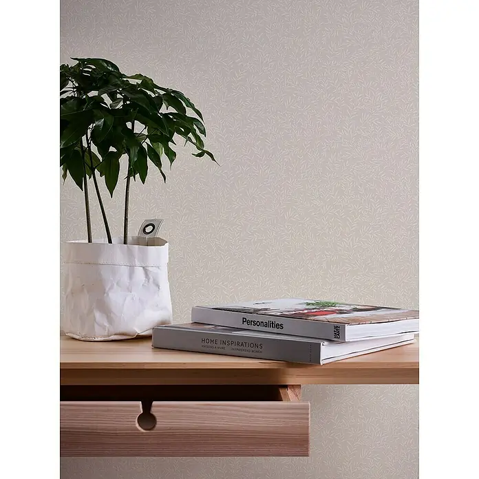 A.S. Création Maison Charme Vliestapete Ranken - Beige-Weiß, Floral, 10,05 x 0,53 m - Nahaufnahme eines Zimmers mit einem Holztisch mit Zimmerpflanze, zwei Büchern und einer Schublade.
