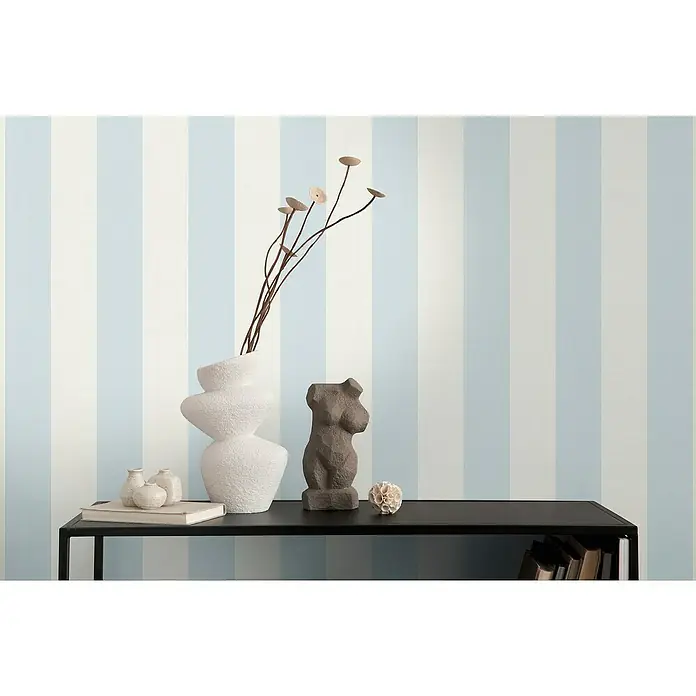 A.S. Création Maison Charme Vliestapete Blockstreifen - Blau-Weiß, Streifen, 10,05 x 0,53 m - Eine elegante Inneneinrichtung mit einer skulpturalen weiblichen Figur, einer abstrakten Vase und dekorativen Elementen auf einem schwarzen Regal.