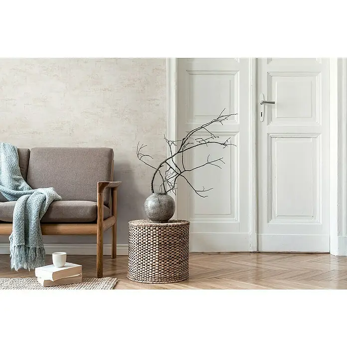 A.S. Création Daniel Hechter 7 Vliestapete Putz - Creme-Beige, Steinoptik, 10,05 x 0,53 m - Beige Couch mit hellblauer Decke und Beistelltisch mit Vase, kombiniert mit eleganten weißen Türen und hellem Parkettboden für ein gemütliches Ambiente.