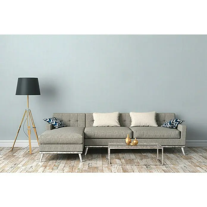 A.S. Création Maison Charme Vliestapete Kleinmuster - Blau-Weiß, Uni, 10,05 x 0,53 m - Das moderne Wohnzimmer verfügt über ein graues Ecksofa mit beigen Kissen, eine Stehlampe und einen Couchtisch aus Glas mit goldenen Vasen.