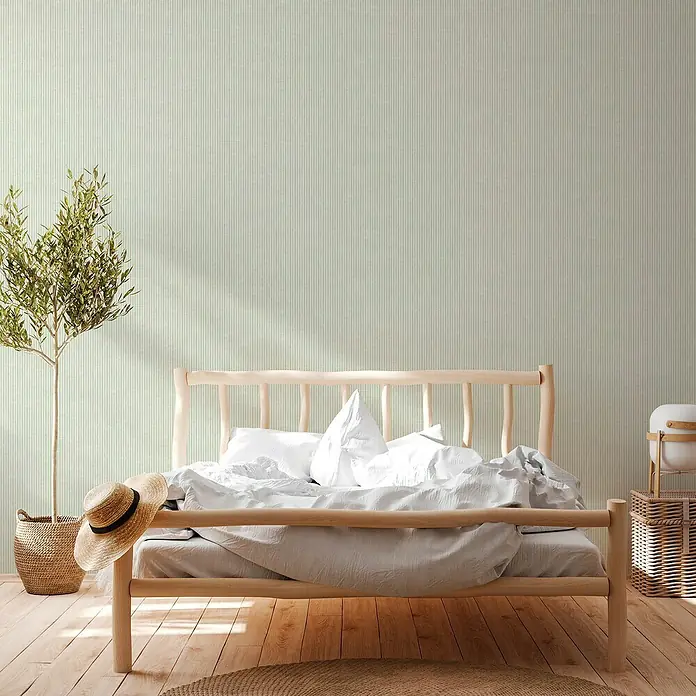 A.S. Création Maison Charme Vliestapete - Grün, Streifen, 10,05 x 0,53 m - Ein helles, minimalistisches Schlafzimmer mit einem schlichten Holzbettenrahmen, weißer Bettwäsche und einer Zimmerpflanze. Die vertikale Tapete verleiht dem Raum eine subtile Textur.