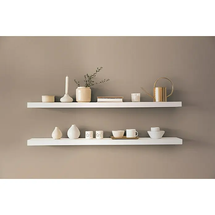 A.S. Création Pintwalls 2 Vliestapete - Braun-Beige, Uni, 10,05 x 0,53 m - Eine Nahaufnahme von zwei weißen Regalen an einer braunen Wand, die mit dekorativen Wohnaccessoires bestückt sind.