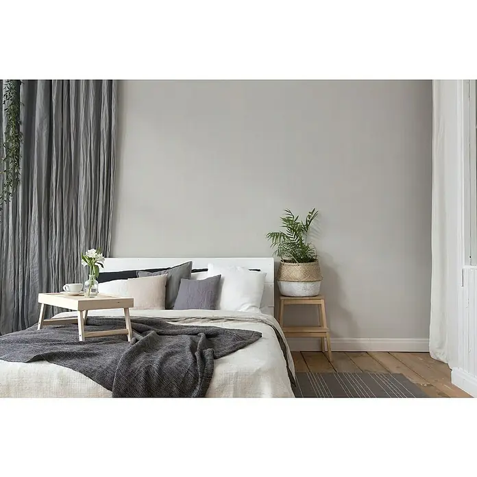 A.S. Création Maison Charme Vliestapete - Grau, Uni, 10,05 x 0,53 m - Ein gemütliches Schlafzimmer mit einem hellen Holzbett, dekoriert mit Kissen, einer grauen Tagesdecke und einem Frühstückstablett mit Blumen.