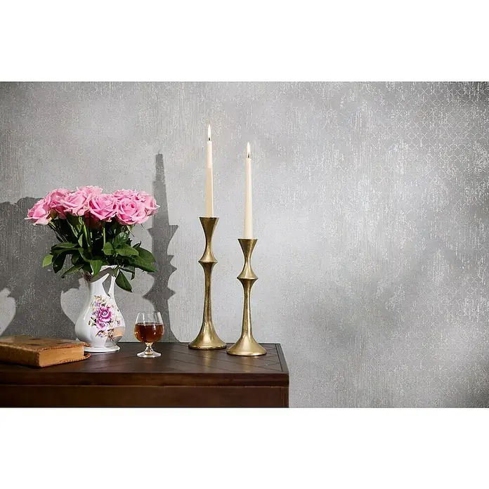 A.S. Création Metropolitan Stories Hot Spots Vliestapete - Grau-Silber-Metallic, Ornament, 10,05 x 0,53 m - Stillleben mit Blumen, Kerzen und Buch auf einem dunklen Holztisch vor einer gemusterten Wand.