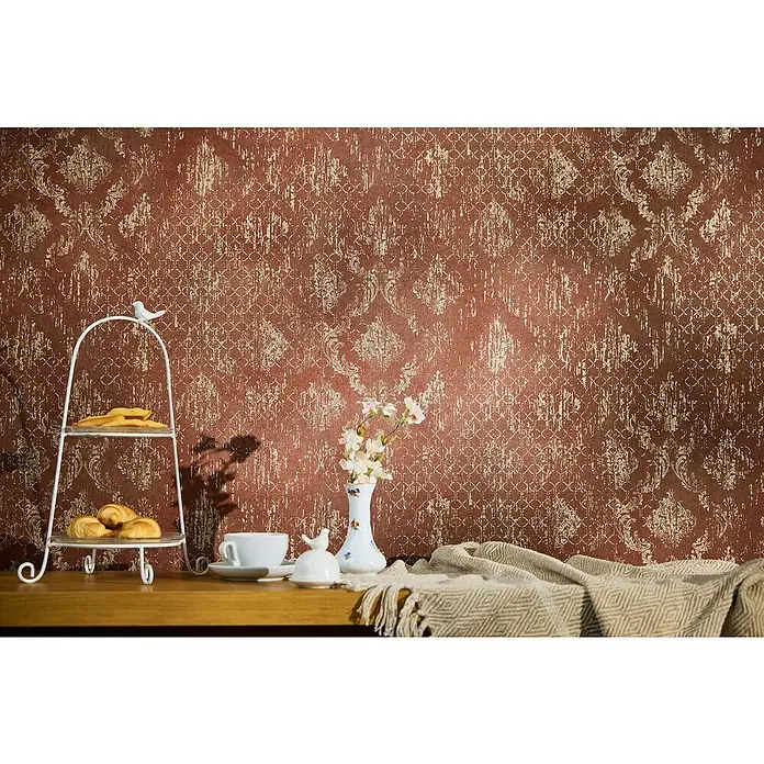 A.S. Création Metropolitan Stories Hot Spots Vliestapete - Rot-Gold-Metallic, Ornament, 10,05 x 0,53 m - Ein elegantes Arrangement mit einem zweistöckigen Gebäckständer, einer Teetasse und einer Vase mit Blumen auf einem Holztisch vor einer dekorativen Wand.