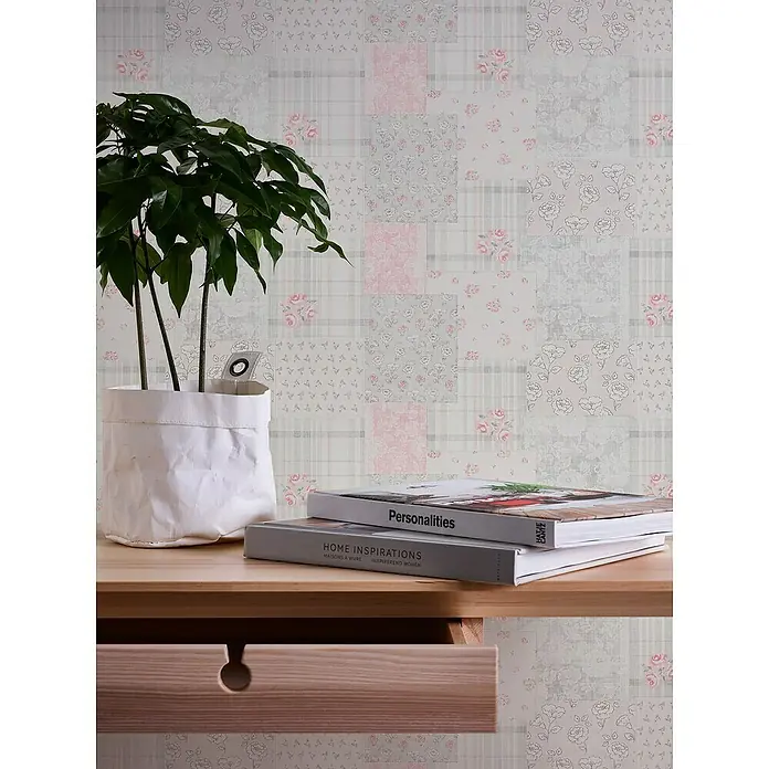 A.S. Création Maison Charme Vliestapete Blümchen-Collage - Grau-Rot-Weiß, Floral, 10,05 x 0,53 m - Eine Nahaufnahme eines Tisches mit einer Pflanze, Büchern und einer Schublade vor einer gemusterten Tapete.