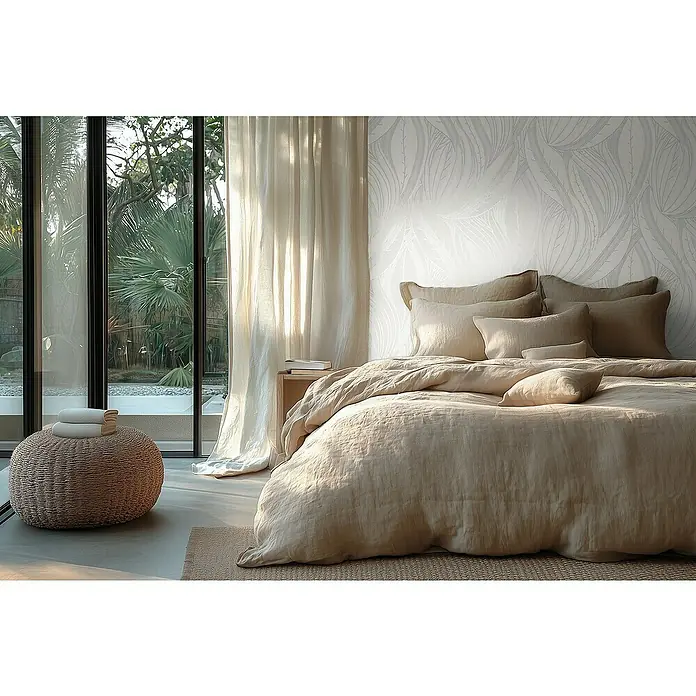 A.S. Création Metropolitan Stories Hot Spots Vliestapete Floral - Weiß-Hellgrau-Silber, Floral, 10,05 x 0,53 m - Einladendes Schlafzimmer mit einem beigen Leinenbett, weichen Kissen und einem gemütlichen Pouf vor dem Fenster mit Blick in den Garten.