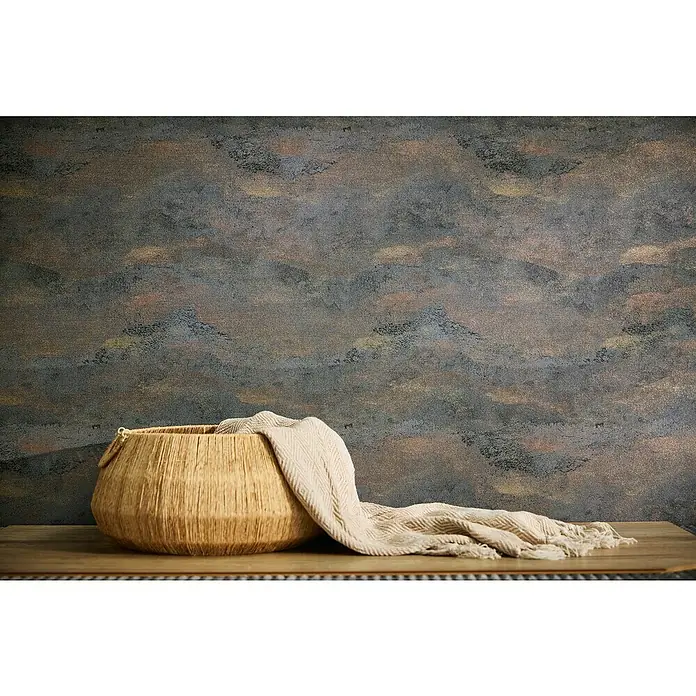 A.S. Création Metropolitan Stories Hot Spots Vliestapete Wellengrafik - Blau-Grau-Metallic, Wellen, 10,05 x 0,53 m - Ein Weidenkorb mit einer cremefarbenen Decke darüber, vor einer strukturierten Wand. Perfekt als Dekoration oder zur Aufbewahrung.