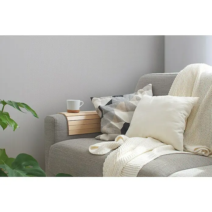 A.S. Création Maison Charme Vliestapete Punkte - Grau-Weiß, Grafisch, 10,05 x 0,53 m - Nahaufnahme von einer gemütlichen Sofaecke mit Kissen, Decken und einem Beistelltischchen mit einer Tasse, die ein entspannendes Ambiente ausstrahlt.