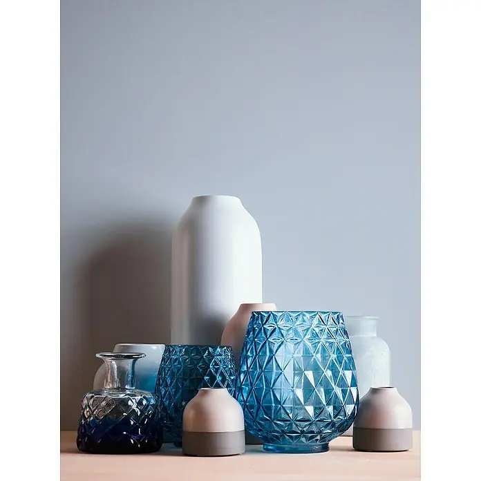 A.S. Création Maison Charme Vliestapete - Blau, Uni, 10,05 x 0,53 m - Eine Anordnung verschiedener Vasen und Behälter in Blau, Weiß und Rosatönen, die eine dekorative und vielseitige Kollektion für Zuhause darstellt.