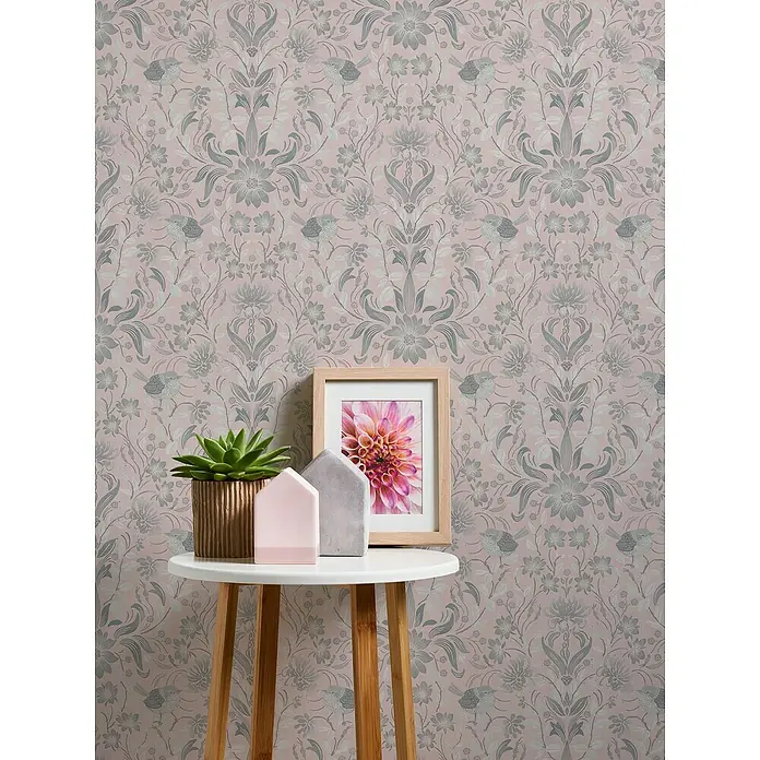 A.S. Création Maison Charme Vliestapete Blumen - Rosa-Grau-Weiß, Floral, 10,05 x 0,53 m - Nahaufnahme von einem kleinen Tisch mit Dekoartikeln und einem gerahmten Bild vor einer verzierten Tapete.