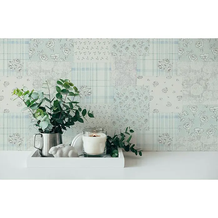 A.S. Création Maison Charme Vliestapete Blümchen-Collage - Blau-Grau-Weiß, Floral, 10,05 x 0,53 m - Stillleben mit Kerze und Eukalyptus-Zweigen auf einem weißen Tablett vor floral gemusterter Wand.