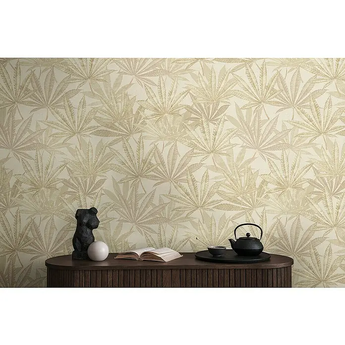 A.S. Création Michalsky Metropolis Vliestapete Hanfblätter - Creme-Beige, Floral, 10,05 x 0,53 m - Ein stilvolles Interieur mit einer Kommode, dekoriert mit einer Skulptur, einem Buch und einem Tee-Set, vor einer Wand mit Blattmuster-Tapete.