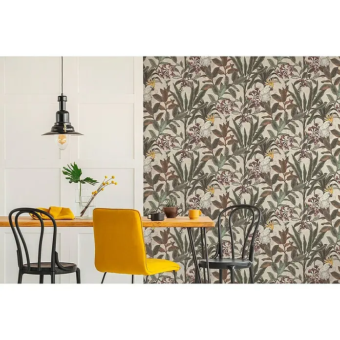 A.S. Création Pintwalls 2 Vliestapete Dschungel - Grün-Creme-Rosa, Floral, 10,05 x 0,53 m - Nahaufnahme eines Raumes mit botanischer Tapete mit Papageienmuster, einem Holztisch und bunten Stühlen unter einer Pendelleuchte.