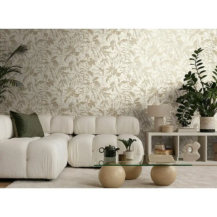 A.S. Création Metropolitan Stories Hot Spots Vliestapete Dschungel - Creme-Beige-Metallic, Floral, 10,05 x 0,53 m - Wohnzimmer mit einem modularen weißen Sofa, einem Couchtisch mit Glasplatte und einer Wand mit floralem Muster.
