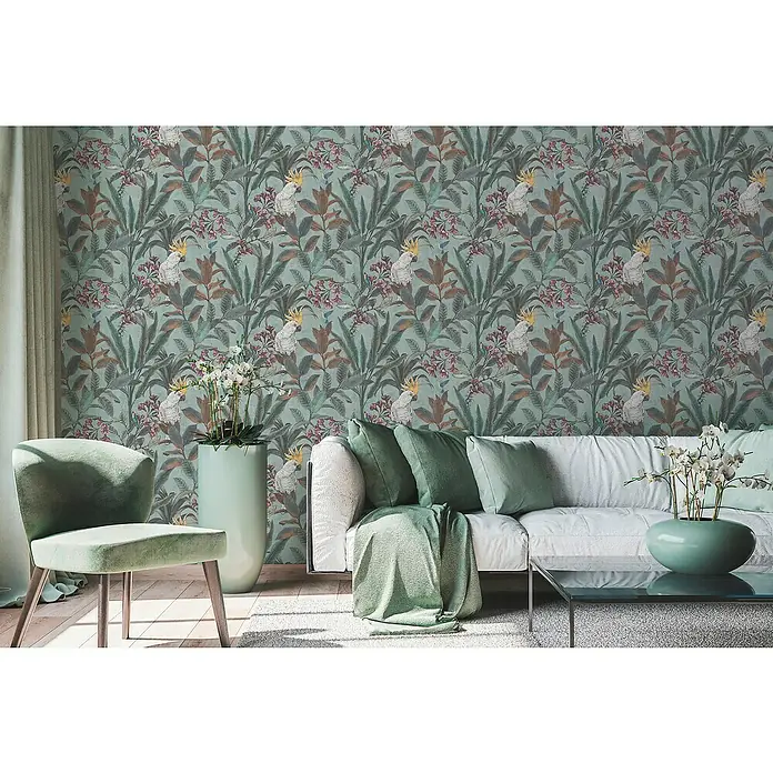 A.S. Création Pintwalls 2 Vliestapete Dschungel - Grün-Blau-Pink, Floral, 10,05 x 0,53 m - Ein Wohnzimmer mit einer Couch, einem Sessel und einem Tisch, dekoriert mit einer Tapete mit Papageien und tropischen Pflanzen.