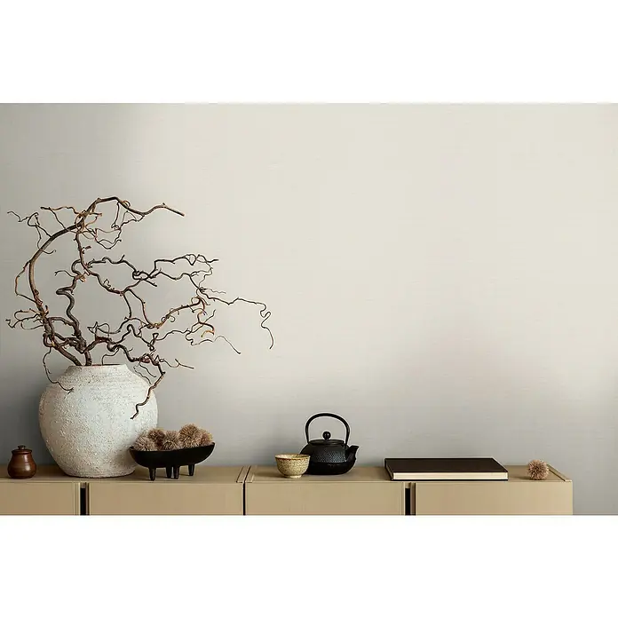 A.S. Création Michalsky Metropolis Vliestapete - Weiß, Uni, 10,05 x 0,53 m - Dekorative Inneneinrichtung mit einer rustikalen Vase, einem Teeset und einem Buch auf einem hellen Sideboard.