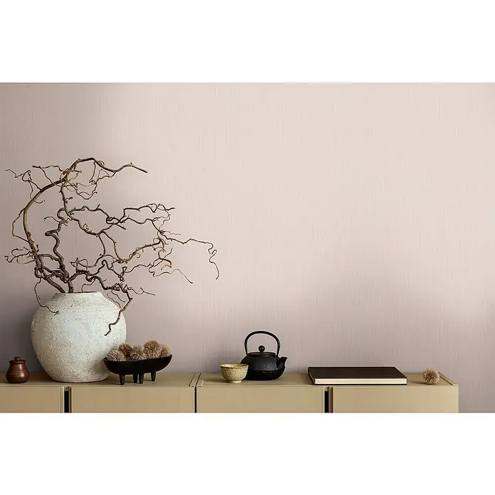 A.S. Création Michalsky Metropolis Vliestapete - Rosa, Uni, 10,05 x 0,53 m - Eine Nahaufnahme eines eleganten Dekorationstableaus mit einer rustikalen Vase, einem Teeservice und einem dunklen Buch auf einer hellen Kommode.