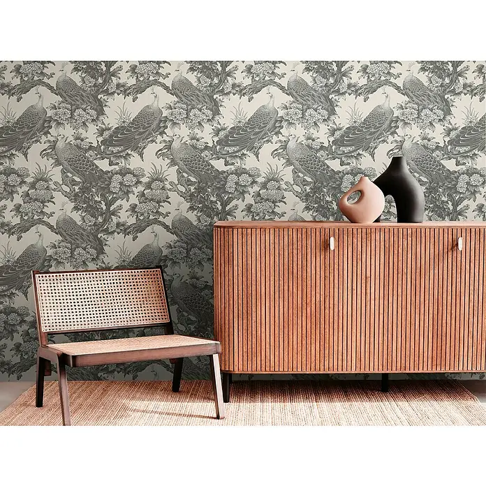 A.S. Création Michalsky Metropolis Vliestapete Dschungel - Grau-Beige, Floral, 10,05 x 0,53 m - Dekorative Holzkommode mit stilvollen Vasen und einem passenden Stuhl auf einem gemusterten Teppich.