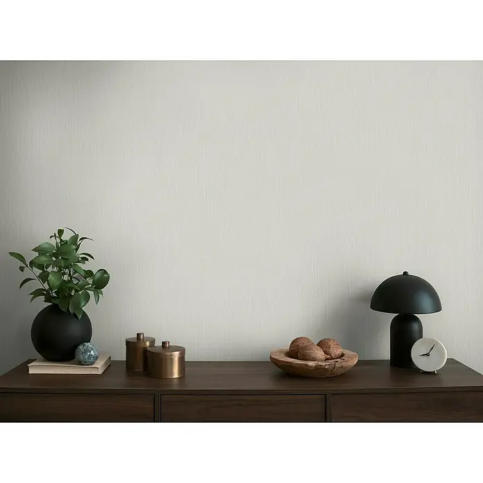 A.S. Création Michalsky Metropolis Vliestapete - Hellgrau, Uni, 10,05 x 0,53 m - Eine Nahaufnahme von Dekorationselementen auf einem dunklen Holzschrank, darunter eine Lampe, eine Pflanze und Schalen.