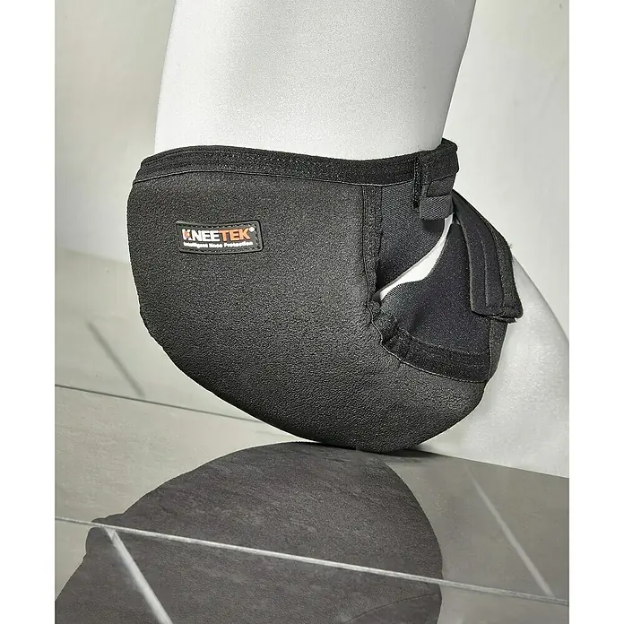 Kneetek Knieschoner Profi Poly - schwarz - Nahaufnahme eines KNEE-TEK Knieschutzes, der am Bein einer Schaufensterpuppe befestigt ist und dessen Reflexion auf einer glänzenden Oberfläche sichtbar ist.