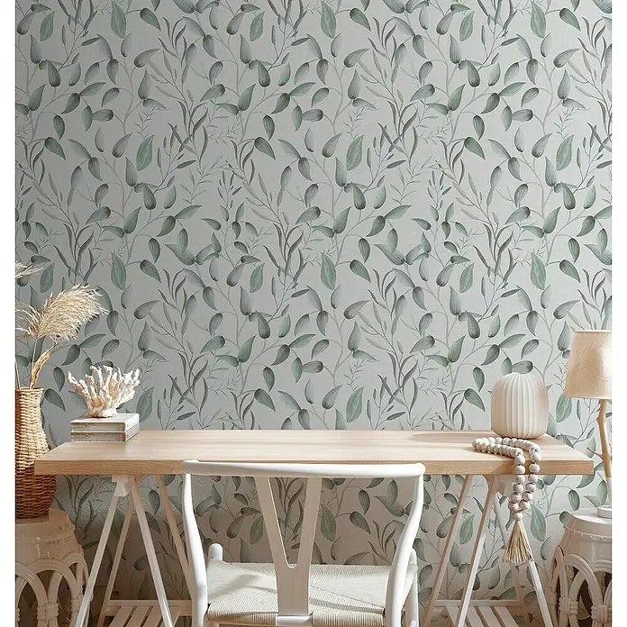 A.S. Création Pintwalls 2 Vliestapete Blätterranke - Grün-Weiß-Grau, Floral, 10,05 x 0,53 m - Nahaufnahme eines Schreibtisches mit floral gemusterter Tapete. Die Tapete dominiert und verleiht dem Raum eine natürliche Eleganz.