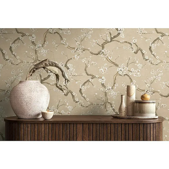 A.S. Création Metropolitan Stories Hot Spots Vliestapete Kirschblüte - Beige-Creme-Braun, Floral, 10,05 x 0,53 m - Elegante Wohnraumszene mit dekorativer Kommode, Vasen und Zweigen vor einer stilvollen Blumentapete.