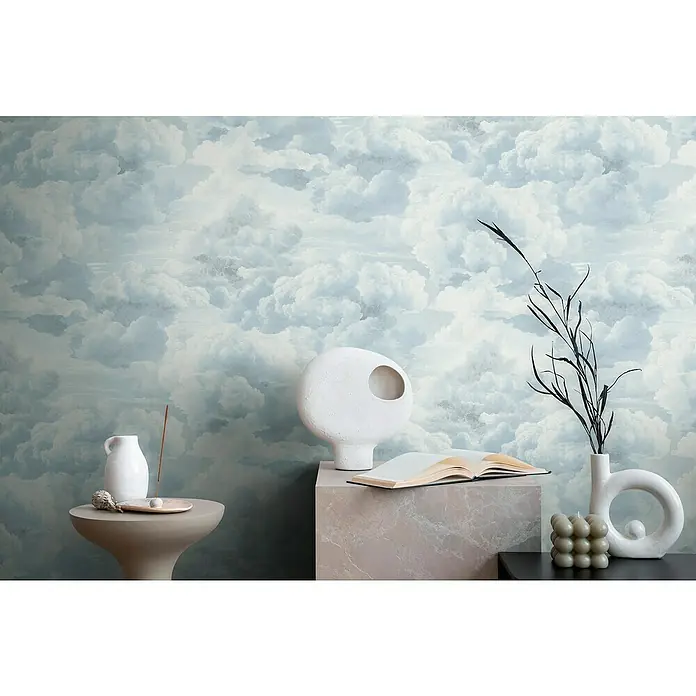 A.S. Création Michalsky Metropolis Vliestapete Wolken - Weiß-Blau, Sonstiges, 10,05 x 0,53 m - Dekorative Szene mit Keramikvase, Buch und Kerze vor einer Wand mit Wolkenmuster, die eine ruhige und ästhetische Atmosphäre schafft.