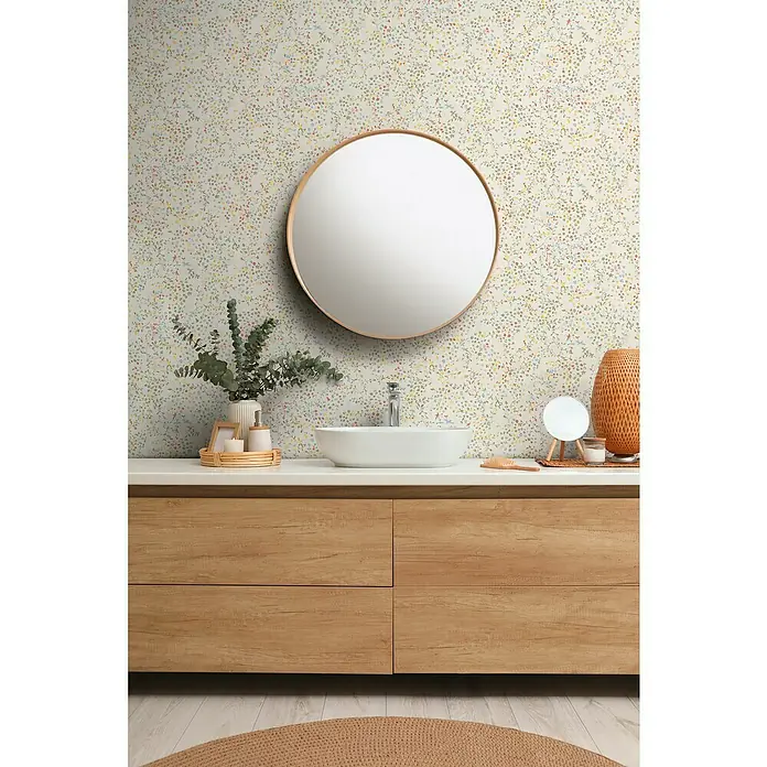 A.S. Création Pintwalls 2 Vliestapete Blumen - Bunt-Creme-Grün, Floral, 10,05 x 0,53 m - Stilvolles Badezimmer mit einem runden Spiegel über einem Waschbecken auf einem Holzunterschrank, ergänzt durch eine zarte Blumentapete.